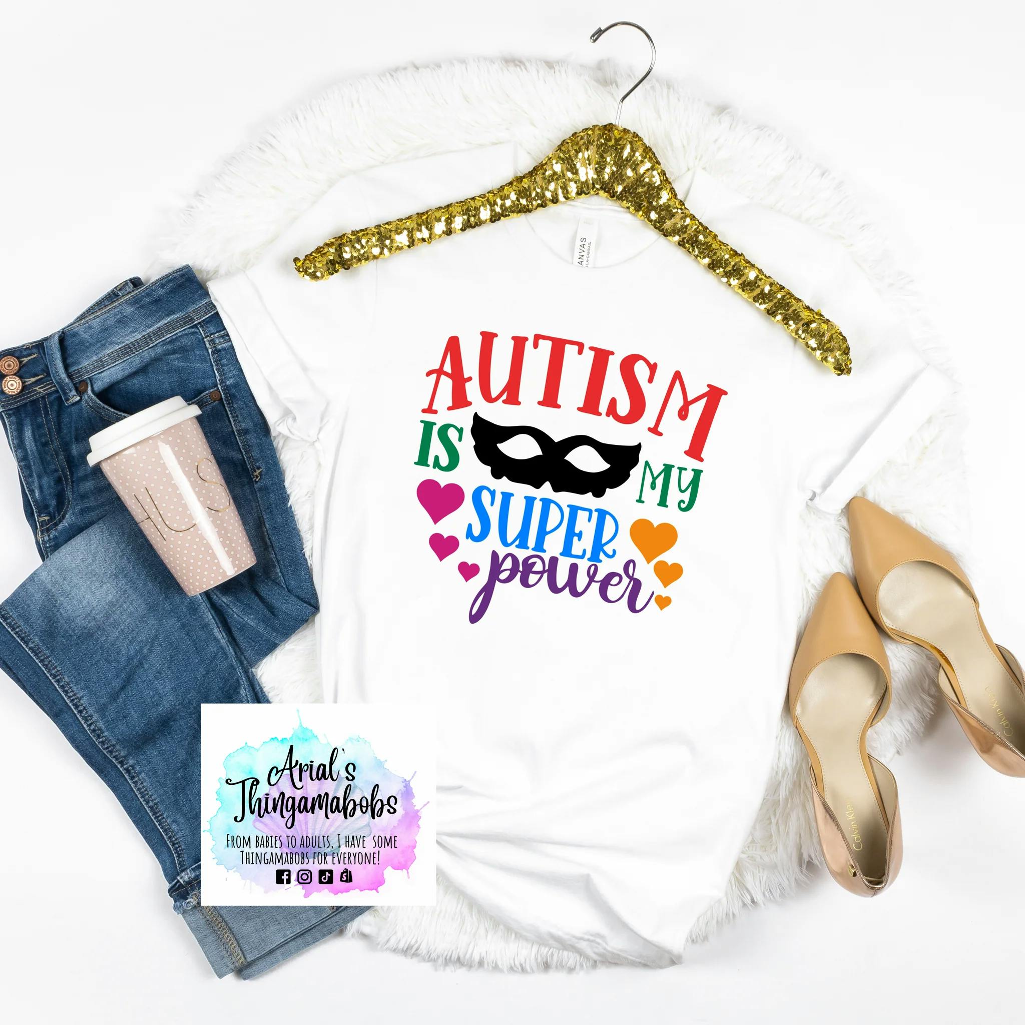 Autism Rocks and Rolls t-shirt. Displays the text  "Autism is my Superpower" in colorful lettering. In the center of the text is a superhero's mask.